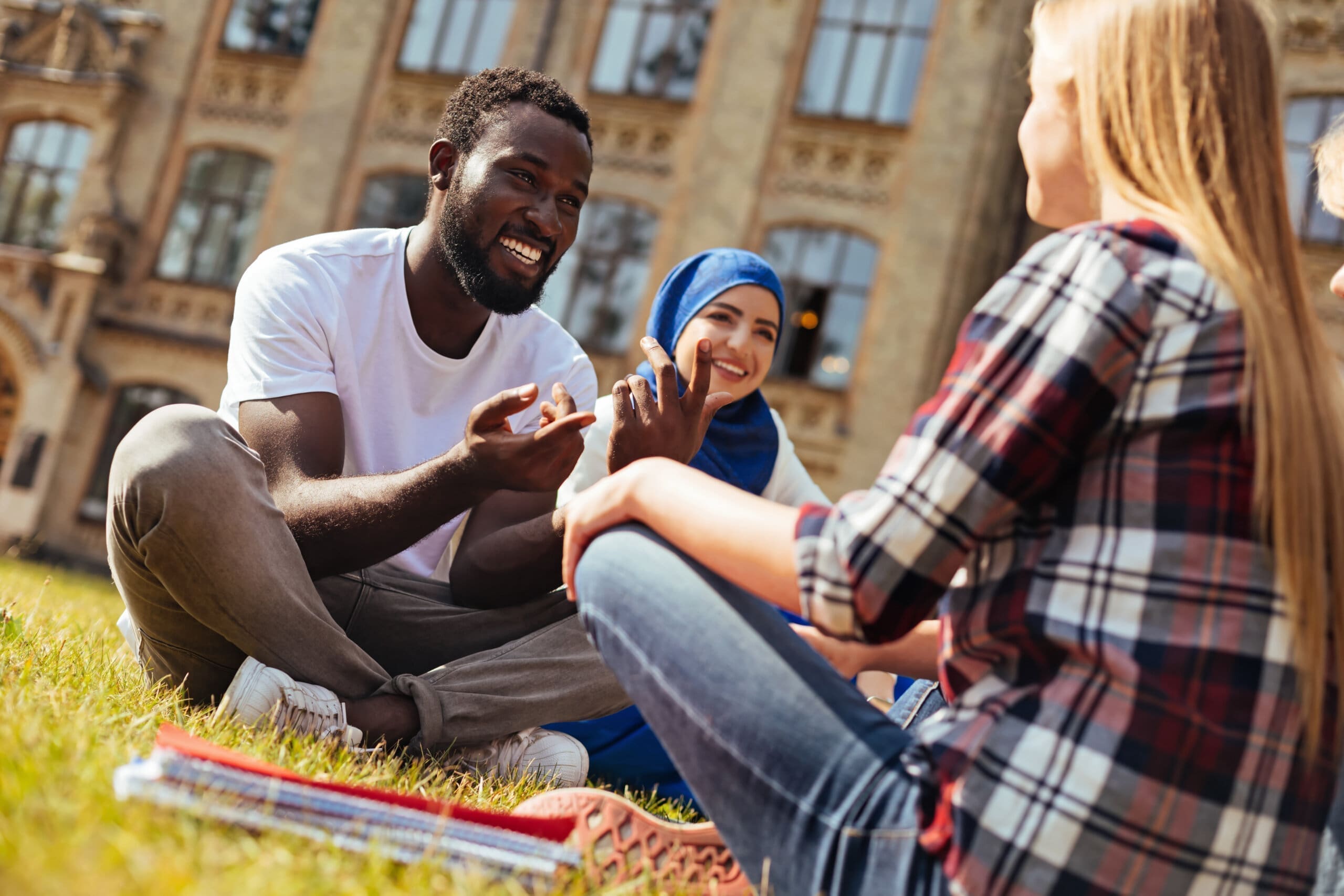 Ambitious motivated charming man meeting his friends after class for working on their project and enjoying the warm weather outdoors